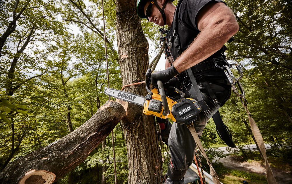 DEWALT Top Handle Chainsaw being used by a man to remove a limb from a tree from a close up view.