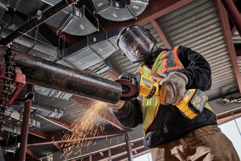 FLATHEAD PADDLE SWITCH SMALL ANGLE GRINDER WITH KICKBACK BRAKE being used by a person in a workshop