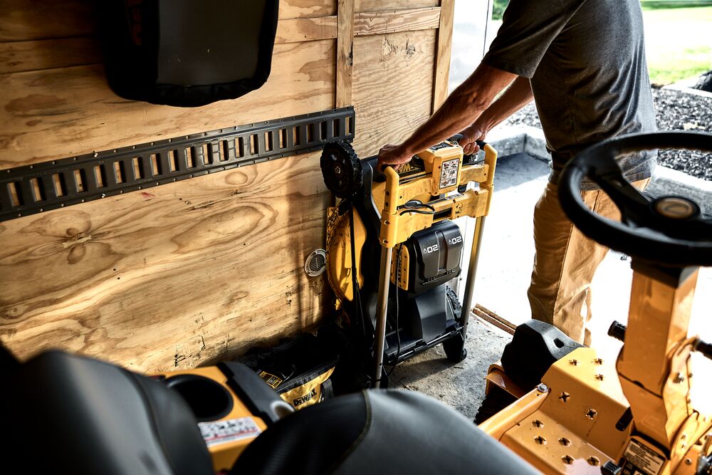 Landscaper stowing DEWALT XR RWD Self-Propelled mower in trailer using one touch folding feature